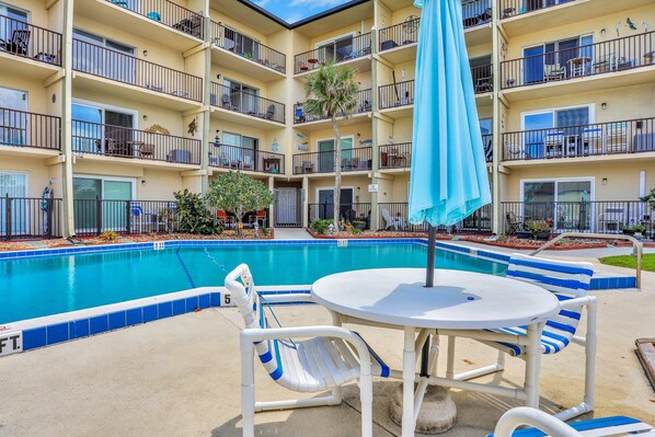 A multi-story hotel with a swimming pool, outdoor seating, and balconies. - Mariners Cove 302 (New Smyrna Beach)