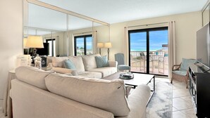 Ett modernt hotellrum med en stor spegel, en soffa, ett soffbord och en TV.