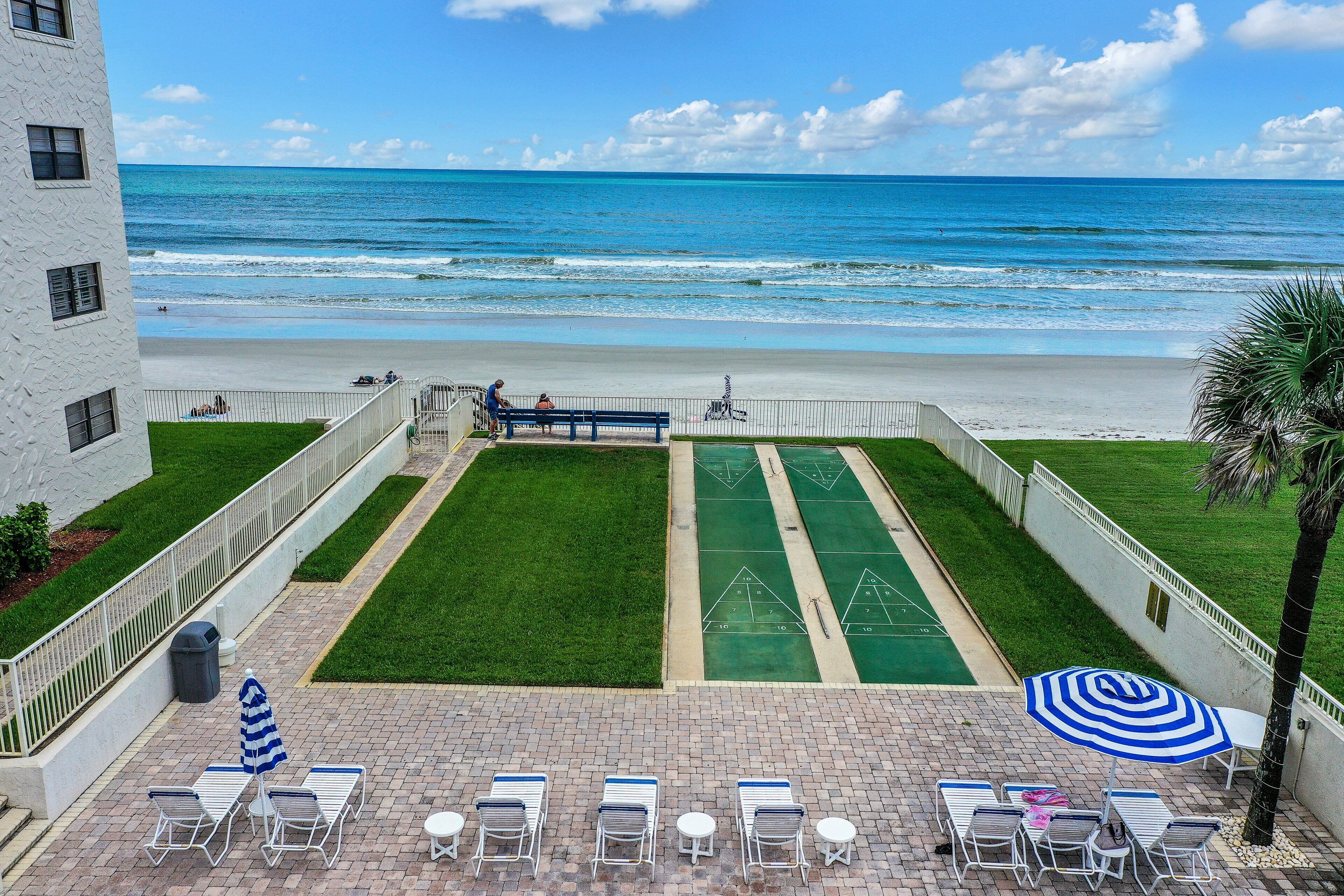 Una terrazza panoramica sul tetto con vista sulla spiaggia e sull'oceano, un campo da shuffleboard e poltrone relax.