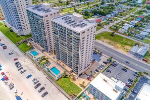 A high-rise hotel with multiple balconies, a swimming pool, and a parking lot. - Daytona Dimucci Twin Towers 404-ocean Oasis (Daytona Beach Shores)