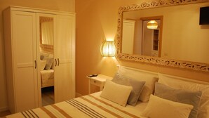 Un dormitorio con cama, mesita de noche, lámpara, armario y espejo.