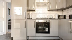 Una cocina moderna con electrodomésticos de acero inoxidable, horno integrado y armarios blancos.