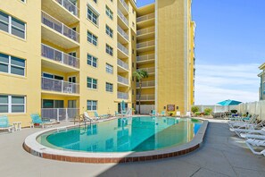 A hotel with a pool, multiple balconies, and lounge chairs. - NSB Ponce de Leon Towers 507 (New Smyrna Beach)