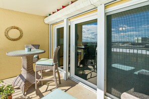 A balcony with wicker furniture, a small table, and a chair. - NSB Ponce de Leon Towers 507 (New Smyrna Beach)