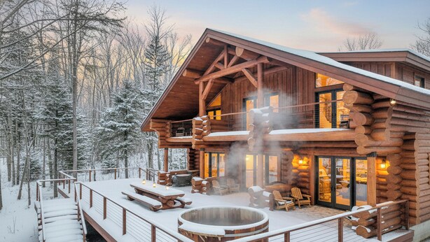 Een houten blokhut met terras, jacuzzi en een zitgedeelte buiten.