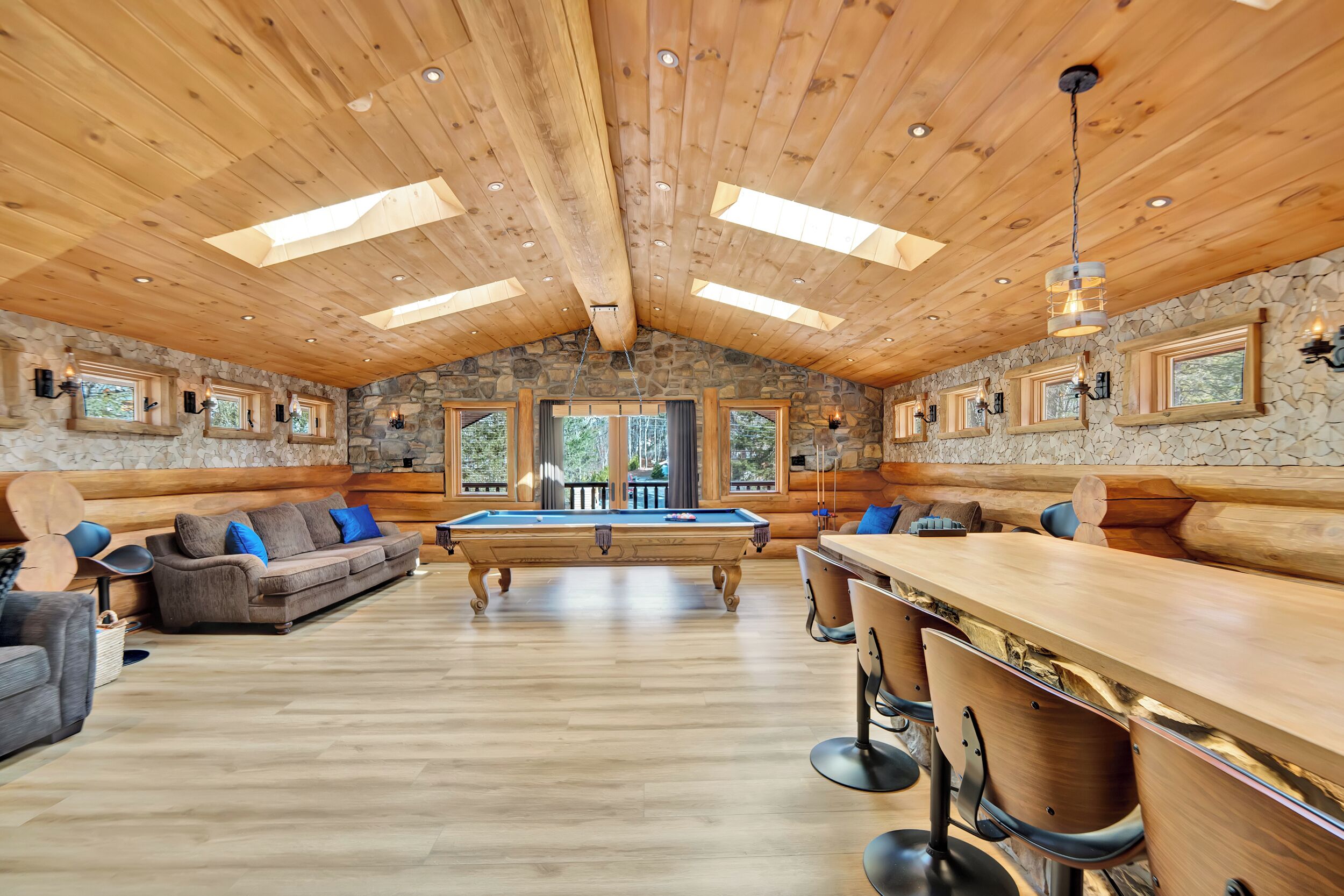A spacious room with a wooden ceiling, stone walls, and a pool table.