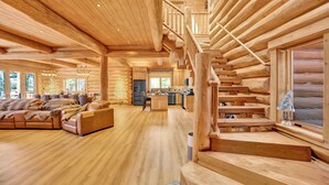 Een ruim houten vakantiehuisje met een ruime woonkamer, een keuken en een trap.