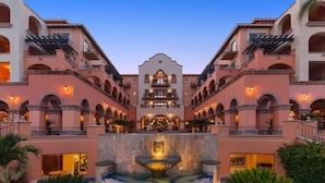 Un hotel con un patio central que cuenta con una fuente, varios balcones e iluminación cálida.