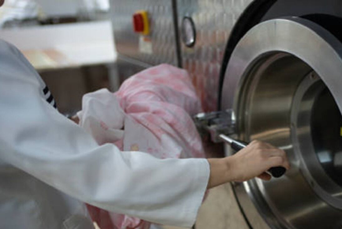Uma pessoa vestindo um casaco branco a operar uma máquina industrial de aço inoxidável.