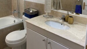 Ein Badezimmer mit Badewanne, Toilette, Waschbecken und einem großen Spiegel.