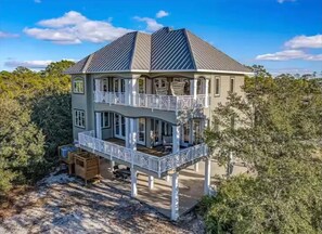 A two-story house with a balcony on the upper floor, surrounded by trees. - Charming Luxury Bayfront Nature Private Paradise: Encanto! (Panacea)