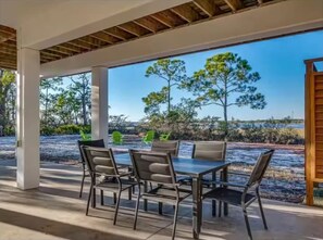 An outdoor seating area with a table and chairs, surrounded by a wooden pergola and a view of trees and a body of water. - Charming Luxury Bayfront Nature Private Paradise: Encanto! (Panacea)