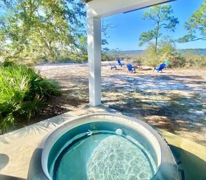 A hot tub with a clear view of the surrounding landscape, including trees and outdoor seating. - Charming Luxury Bayfront Nature Private Paradise: Encanto! (Panacea)