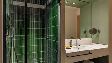 A modern bathroom with green-tiled walls, a white sink, and a mirror.