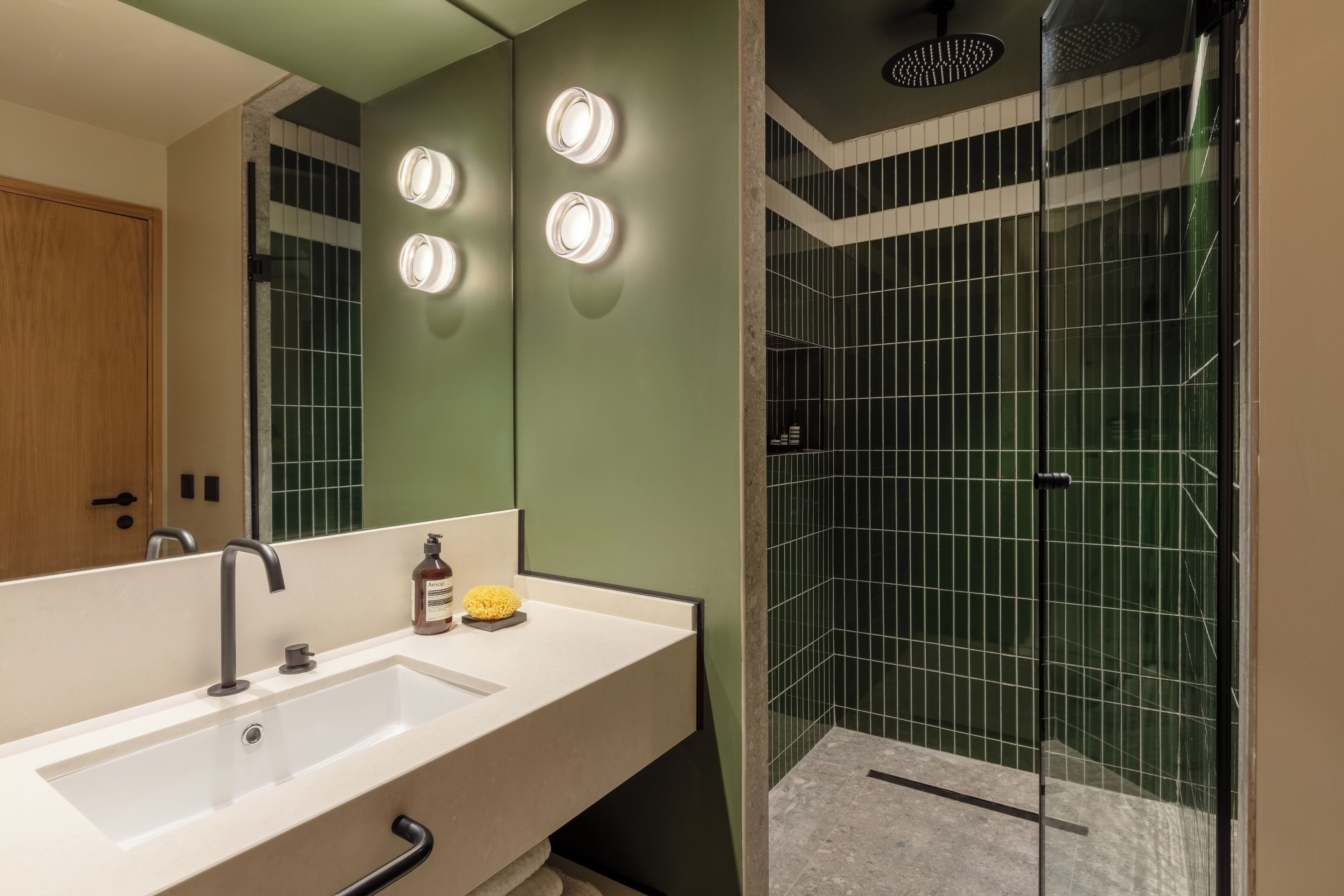 Une salle de bain moderne avec un grand miroir, un lavabo et un espace douche.