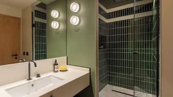 Un baño moderno con un espejo grande, un lavamanos y una zona de ducha.