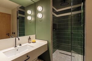 Un bagno moderno con un ampio specchio, un lavandino e uno spazio doccia.