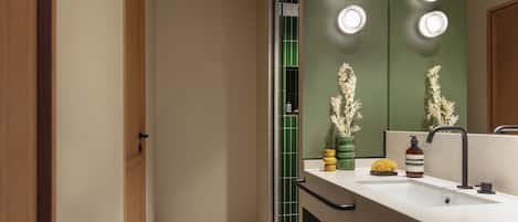 A modern bathroom with a large mirror, a sink, and a vanity. There are three lights above the mirror and a towel rack below it.