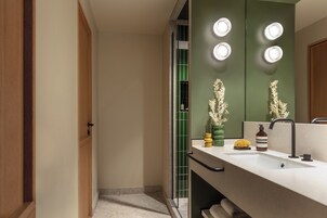 A modern bathroom with a large mirror, a sink, and a vanity. There are three lights above the mirror and a towel rack below it.