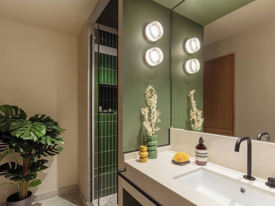 Un baño moderno con un espejo grande, dos lavamanos y una planta en maceta.