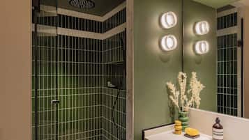 Een moderne badkamer met een douchegedeelte, een wastafel met spiegel, en een vaas met gedroogde bloemen.