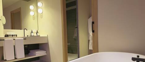 A modern bathroom with a large bathtub, a vanity with a mirror, and a shower area.