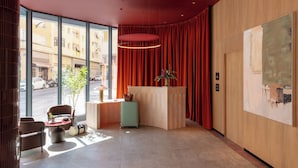 En moderne lobby med reception, siddeområde og store vinduer med udsigt til gaden.