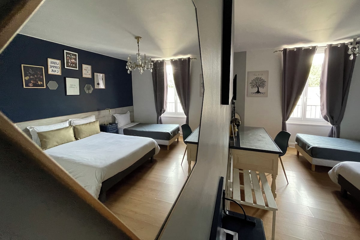 Ett hotellrum med två sängar, ett matbord och en kristallkrona.