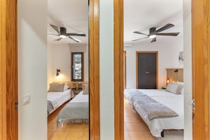 A bedroom with two beds, a ceiling fan, a nightstand, and a window. - Arizona's Bay Holiday Home with Sea Views, Hot Tub, and Private Terrace (Mogán)