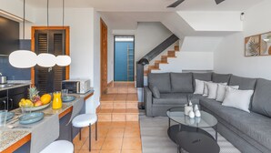 A modern living space with a kitchen, dining area, and a grey sofa. - Arizona's Bay Holiday Home with Sea Views, Hot Tub, and Private Terrace (Mogán)