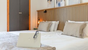 A bedroom with a bed, a laptop, a wardrobe, and a wall-mounted light. - Arizona's Bay Holiday Home with Sea Views, Hot Tub, and Private Terrace (Mogán)