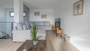 Un salon moderne avec un canapé gris, une table basse en bois et un petit sapin de Noël.