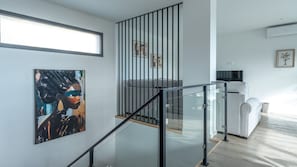 Un intérieur moderne avec un escalier, un canapé et des œuvres d’art accrochées aux murs.