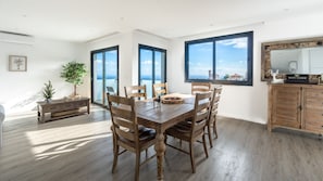 Un coin repas avec une table et des chaises en bois, de grandes fenêtres offrant une belle vue, un meuble en bois et une plante.