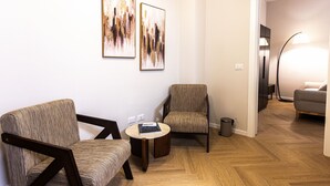 A modern living room with two patterned armchairs, a small round table with a book, and a floor lamp. - Morazzone suite - Chinatown (Milano)