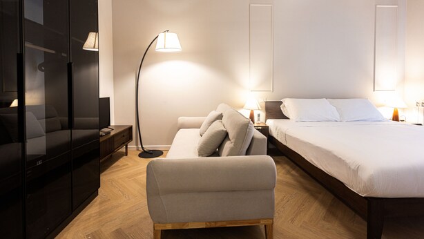 A modern bedroom with a bed, a sofa, a TV, and a floor lamp. - Morazzone suite - Chinatown (Milano)