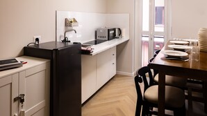 A compact kitchen with a refrigerator, microwave, and sink. There is a dining table with chairs and a window overlooking a balcony. - Morazzone suite - Chinatown (Milano)