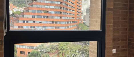 A view through a window of a multi-story building with a unique angular design, a brick wall, and a street scene below.