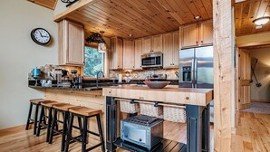 Eine moderne Küche mit Holzausstattung, einer zentralen Kochinsel mit Barhocker, einem Einbauofen und einer Mikrowelle.
