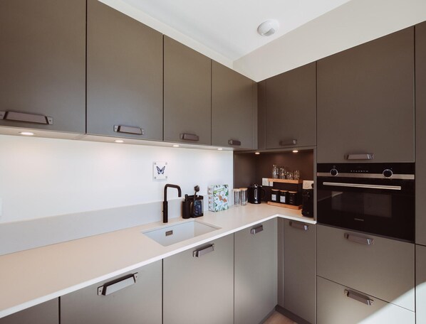 A modern kitchen with grey cabinets, a white countertop, and a built-in oven. - Holiday Home for 6 People in the Heart of Perigord (Saint-Medard-d'Excideuil)