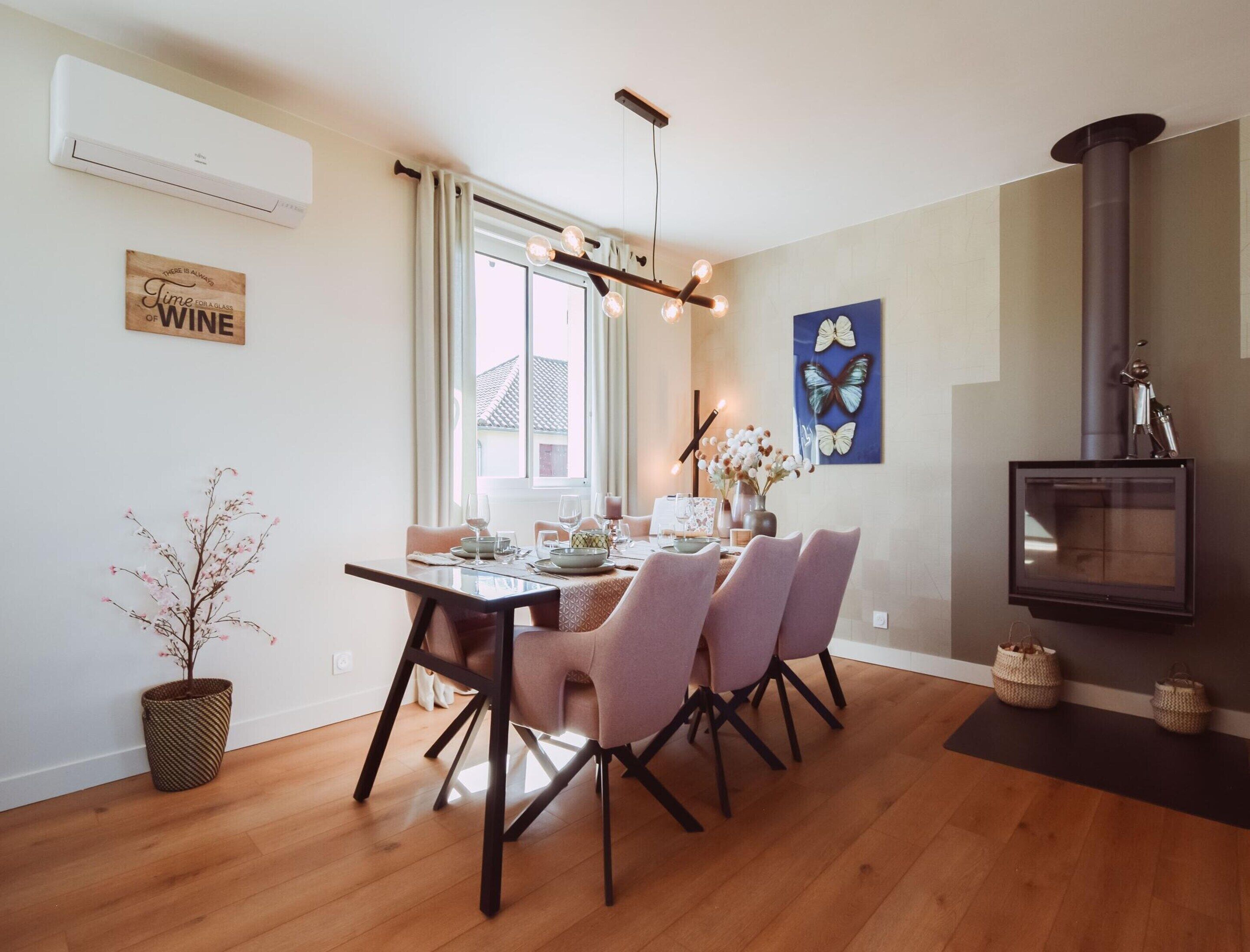 A dining area with a wooden table, pink chairs, and a modern chandelier.