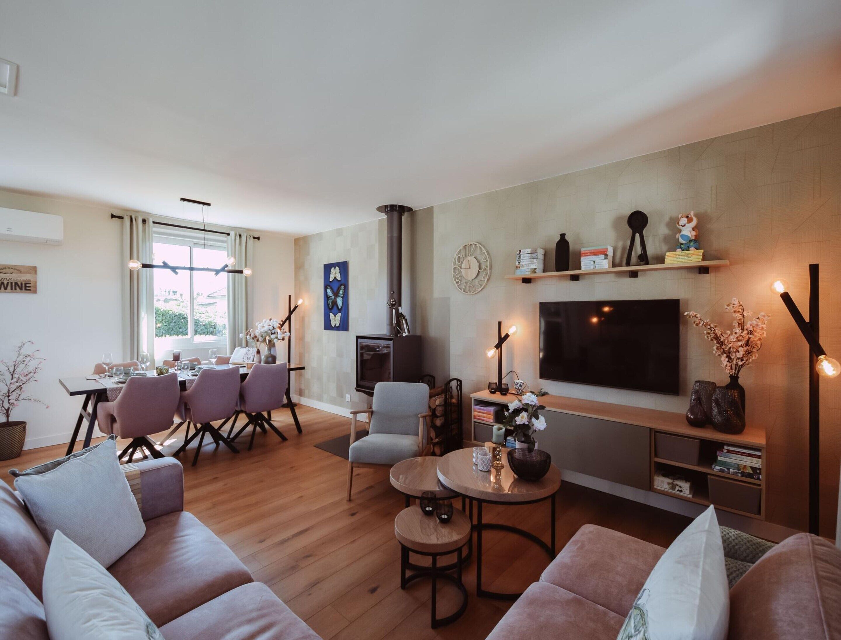 Una sala moderna con sofá, mesa de centro y televisor. Hay un comedor con sillas y una mesa.