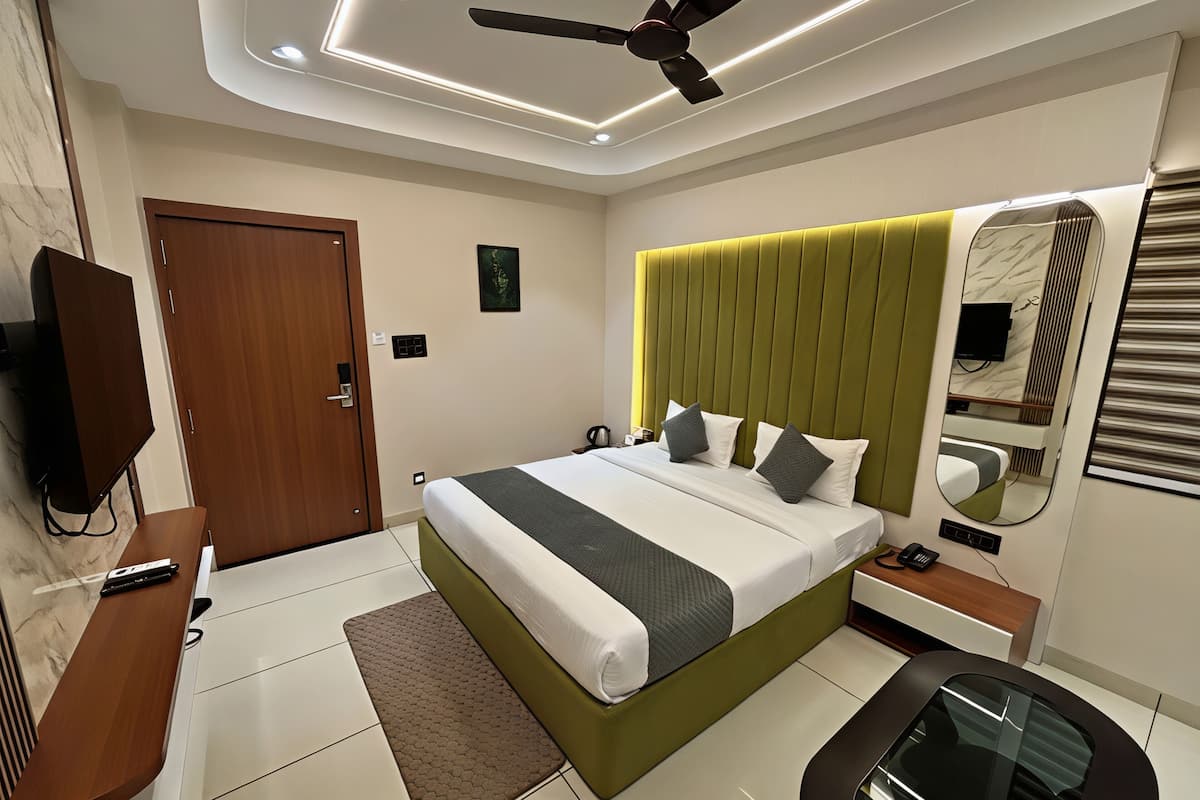 Une chambre d’hôtel moderne équipée d’un grand lit, d’un bureau, d’une chaise, d’un ventilateur de plafond et d’une télévision.