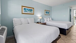Ein Hotelzimmer mit zwei Betten, einem Nachttisch mit Lampe sowie zwei gerahmten Bildern an der Wand.