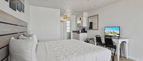A hotel room with a bed, desk, and TV.
