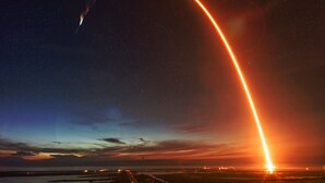 Ein Raketenstart mit einer leuchtend orangefarbenen Bahn vor einem sternenübersäten Nachthimmel.