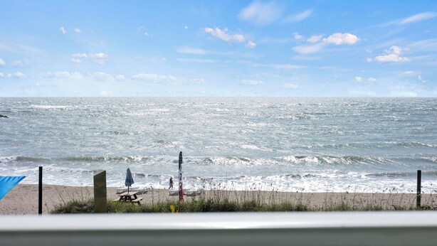 A beach with a clear sky, waves, and a picnic table. - Oceanfront Inn Room #23 - Ocean View Balcony, King Bed (Fort Pierce)