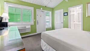 Een slaapkamer met een bed, een bureau met lamp en een raam met zonwering.