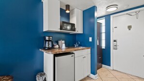 A compact kitchen with a microwave, coffee maker, and dishwasher. - Oceanfront Inn Room #17- Ocean View Balcony, King Bed (Fort Pierce)