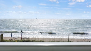 Une plage avec une table de pique-nique et un parasol, un mât pour drapeau et une clôture.
